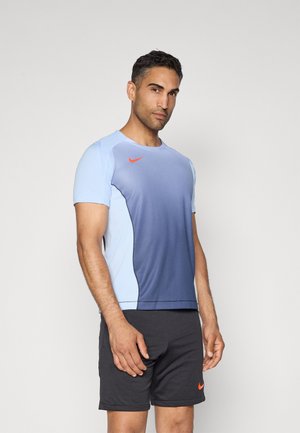 T-shirt d'entraînement Nike dégradé du bleu clair au bleu foncé, avec des manches courtes et un logo orange ; associé à un short noir.