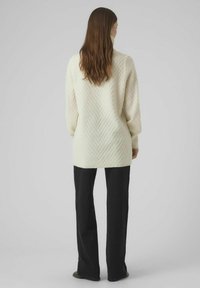 Pikk, sooja kudumine off-white värviga, millel on tekstuuriga chevron mustriga, laia varrukaga ja kõrge kaelusega. Läheb kokku mustade pükstega.