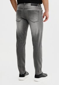 Szare dżinsy o wąskim kroju, z dwoma tylnymi kieszeniami, delikatnym wyblaknięciem i czystym wykończeniem. W połączeniu z czarnym obuwiem.