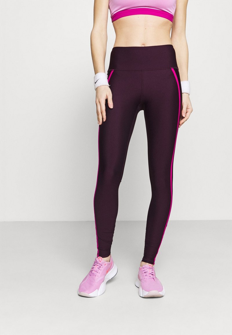Höga, mörklila leggings med rosa sidostrecken, tillverkade av elastiskt tyg. Bärs tillsammans med en matchande rosa sport-bh och rosa träningsskor.