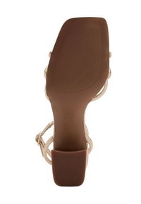 Beige högklackad sandal med en mjuk, brun gummisula. Har tunna remmar och en blockklackdesign för stabilitet.