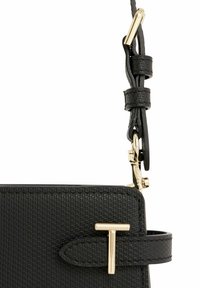 Borsa nera con texture, dotata di hardware in tonalità oro, caratterizzata da un evidente clasp a forma di "T" e una tracolla regolabile con clip e dettagli in pelle.