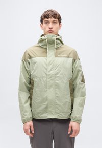 Ανοιχτό πράσινο μπουφάν με κουκούλα, με σκούρες πράσινες λεπτομέρειες, ελαστικές μανσέτες και φερμουάρ μπροστά. Κατασκευασμένο από ελαφρύ, υφή ύφασμα.