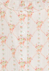 Hvitt bluse av stoff med blomsterbroderi i rosa og grønt, med en rynket krage og knappelukking foran.