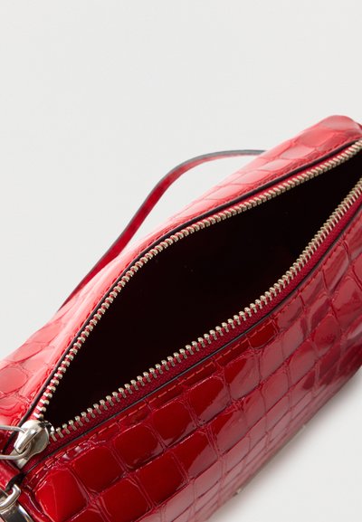 Κόκκινη, γυαλιστερή τσάντα με υφή κροκόδειλου, ανοιχτό ασημί φερμουάρ που αποκαλύπτει σκοτεινό εσωτερικό, λεπτό λουρί και ορθογώνιο σχήμα.