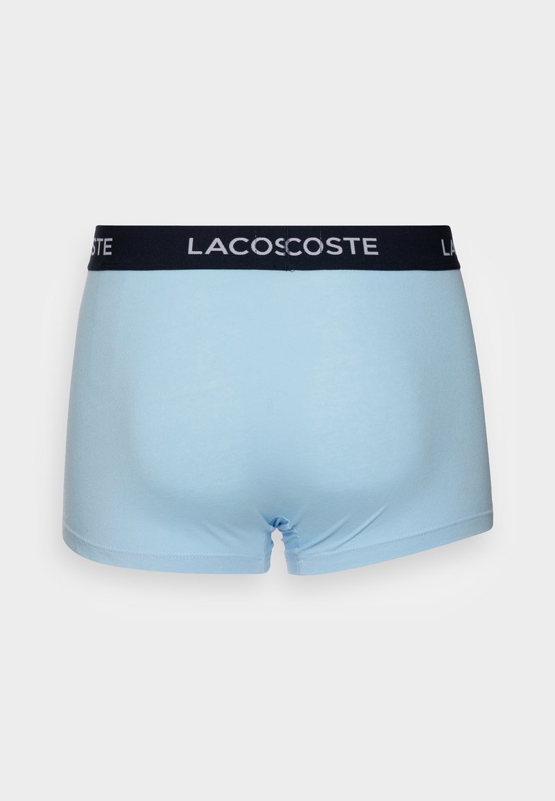 Lichtblauwe katoenen boxershorts met een zwarte elastische tailleband waarop het 'LACOSTE' logo in het wit is gedrukt. Gladde textuur, aansluitend ontwerp.