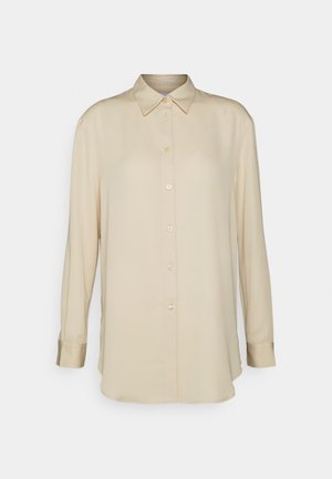 Chemise à manches longues couleur crème en tissu doux et lisse. Comprend un col classique, une patte de boutonnage sur le devant et des manches avec poignets. Aucune motif ou accent visible.