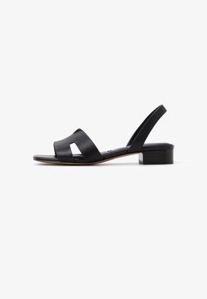 Sandali neri in pelle con due larghe fasce e punta aperta. Tacco basso a blocco, design minimalista e texture liscia.