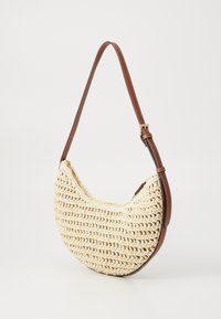 Hobo bag with a woven cream exterior, brown leather strap, and gold hardware accents. Features a crescent shape and textured detail.