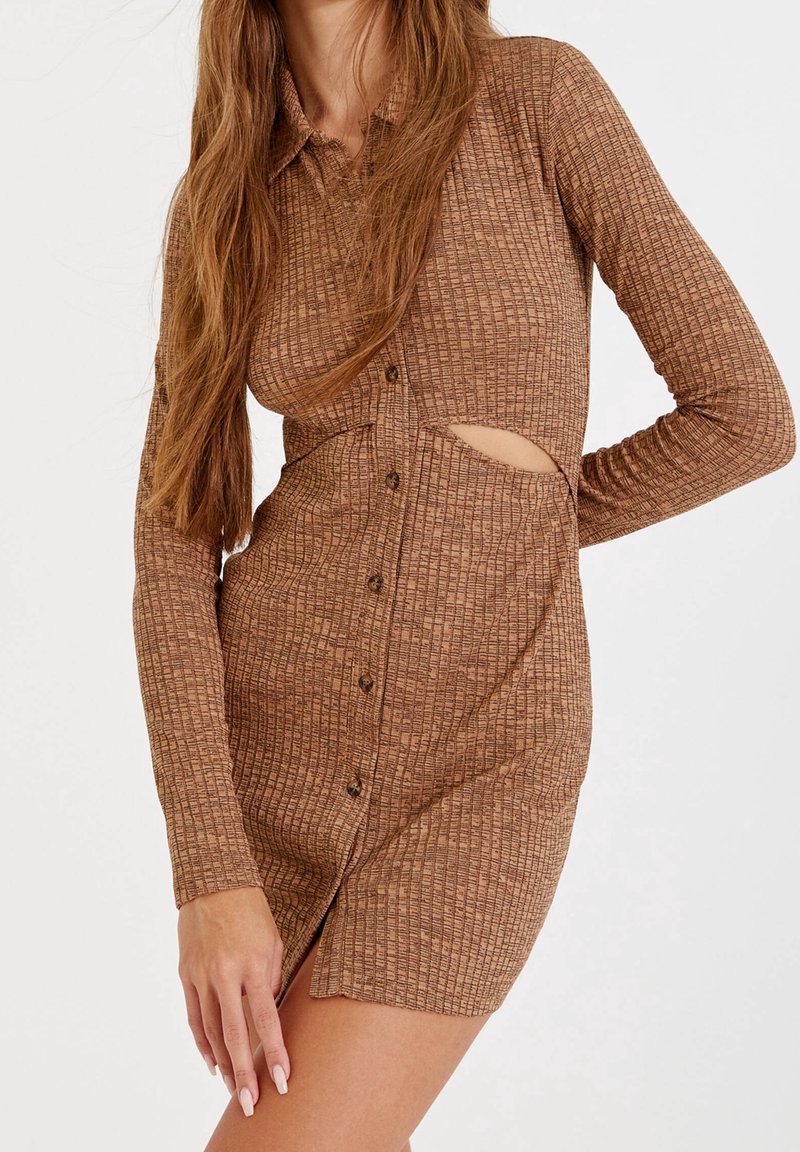 Robe à manches longues, en ribbed marron avec un col et une fermeture à boutons. Présente une découpe sur le côté et une finition texturée pour plus de détails.