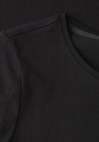 T-shirt noir en coton à col rond et à manches courtes. Texture lisse, design minimaliste et détails surpiqués au niveau du col.