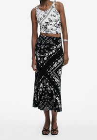 Mustavalkoinen kukkakuosiselkä cropped-top, jossa on solmittavat hihnat, yhdistetty pitkiin, kuviollisiin hameeseen, joka esittelee vaihtelevaa kukkakuosisia muotoa ja designia.