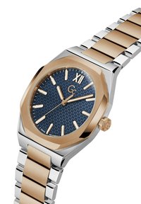 Dvi tonos metalinė riešo laikrodžio su mėlynu tekstūruotu ciferblatu, auksiniais valandų žymekliais, romėniškąja XII, ir trimis auksinėmis rodyklėmis, rodančiomis 10:10:38.