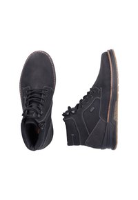 Bottines noires en cuir avec un bout arrondi, semelle en caoutchouc robuste et coutures blanches contrastantes. Caractéristiques d'une conception à lacets et d'accents latéraux.