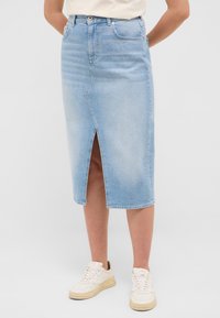 Svetlomodrá denim midi sukňa s predným rozparkom, piatimi vreckami a pútkami na opasok, v kombinácii s bielymi teniskami. Hladká textúra, ležérny dizajn.