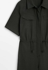 Dark grey jumpsuit with short sleeves, two chest pockets, and a cinched waist featuring adjustable drawstrings. Fabric appears smooth.