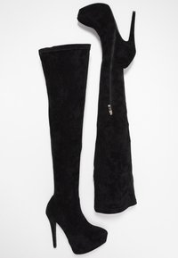 Botas negras de ante sobre la rodilla con acabado texturizado, tacón de aguja alto y detalle de cremallera lateral.