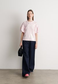 Heled roosa sädelev oversize särk, millele on kombineeritud tume sinine laiemat põlve püksid, roosa jalanõud ja väike must käekott. Lihtne disain.