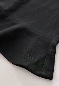 Zwarte stoffen top met een gladde textuur, afgeronde randen en een subtiel logo op de zoom genaaid. Minimalistisch ontwerp zonder patronen.