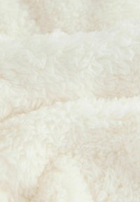 Witte, pluizige stof met een zachte textuur, gekenmerkt door een mix van lange en korte vezels, waardoor een gezellige, luxe uitstraling ontstaat.