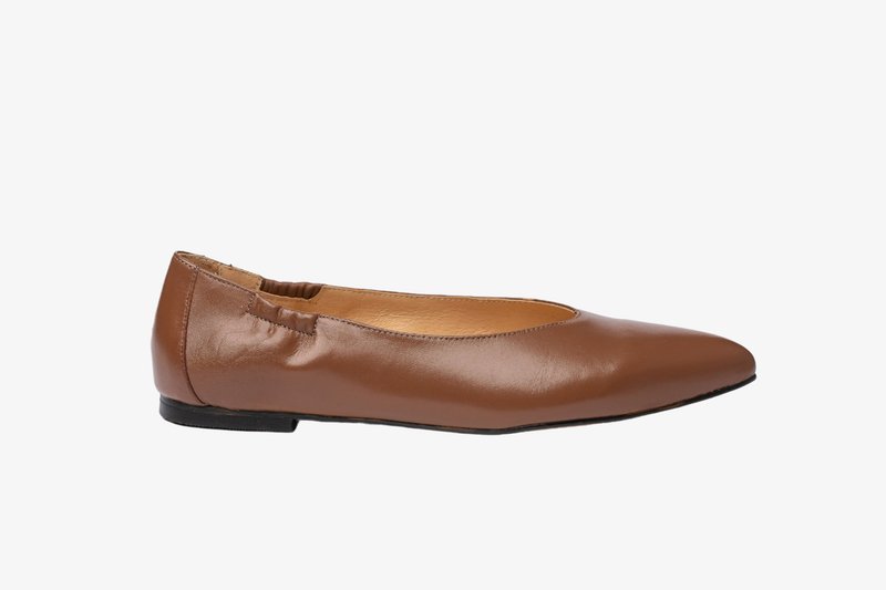 Zapato plano de cuero marrón con punta puntiaguda, abertura elastizada y tacón negro bajo, que presenta una superficie lisa y un diseño minimalista.