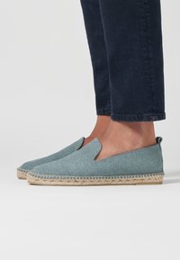 Lichtgroene instap-espadrilles van textiel, met een geweven jute zool en elastische zijpanelen. Draag je met een donkere denim broek.