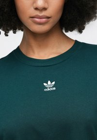 Grøn bomuld T-shirt med rund halsudskæring, der har et hvidt Adidas-logo på brystet. Glat stof med en klassisk pasform.