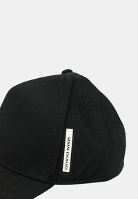 Cappellino da baseball nero con design strutturato, realizzato in tessuto. Presenta un'etichetta con logo sul lato e una visiera curva. Finitura testurizzata.
