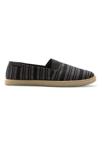 Svart espadrille-liknande slip-on sko med vita ränder, med en jutesula och elastiska sidopaneler för flexibilitet och komfort.