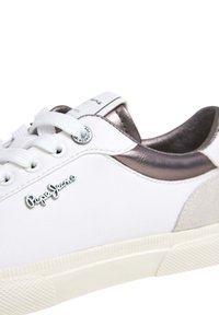Sneakers bianchi con tomaia in pelle liscia, dettagli in bronzo metallico, pannello in suede grigio e lacci bianchi. Presenta il logo "Pepe Jeans" sul lato.