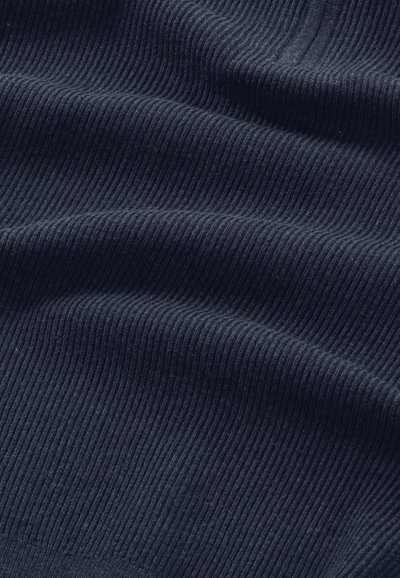 Tumma sininen ribbikangas pehmeällä tekstuurilla, jossa näkyy aaltoilevia taitteita ja kirkas neulekuvio.