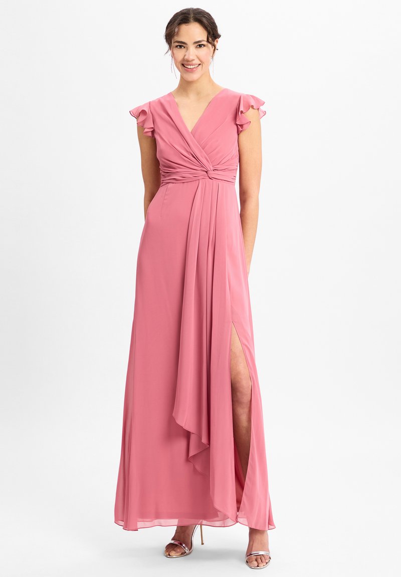 Langes, pinkes Chiffonkleid mit gedrehtem Oberteil, schwingenden Ärmeln und einem seitlichen Schlitz. Akzentuiert mit einer glatten, fließenden Textur.