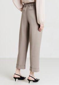 Pantaloni tapered grigio chiaro con vita elastica e orli rifiniti. Tessuto liscio, dotato di due tasche posteriori e una vestibilità tailored.