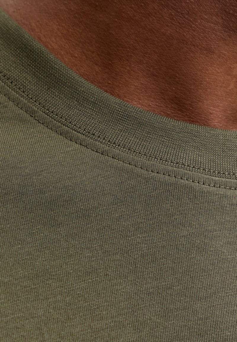 Alyvuogių žalios spalvos medvilninė marškinėliai su ribbingu aplink apvalų kaklo iškirpimą. Švelni tekstūra su smulkiais siūlių akcentais ties apykakle.