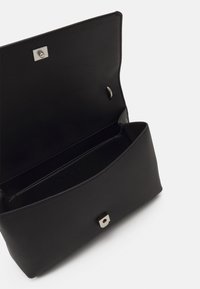 Svart texturerad clutchväska med ett slätt inre, utrustad med en metallisk knappknäppning och en rektangulär silverdetalj på framsidan.