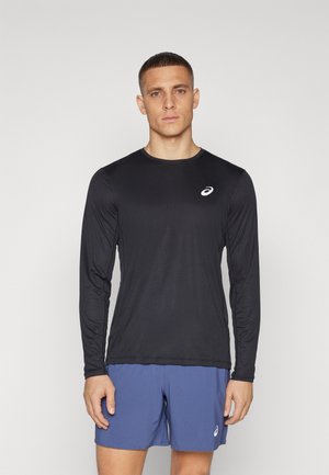 Črna dolgosleeve športna majica z subtilnim sijajem, ki ima okroglo ovratnik in majhen bel logotip na zgornji levi prsni strani.