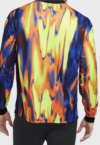 Długorękawowa koszulka sportowa z żywym, abstrakcyjnym wzorem w kolorach żółtym, pomarańczowym, niebieskim i czarnym, wykonana z gładkiego, syntetycznego materiału.