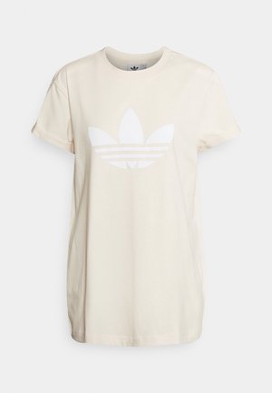Cream-colored cotton t-shirt with short sleeves, featuring a large white Adidas logo and three horizontal stripes beneath the logo.