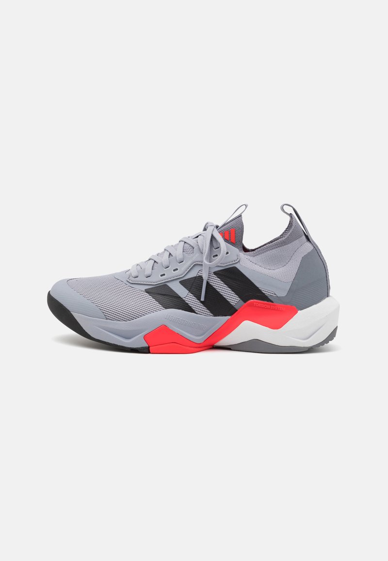 Gray athletic shoe with black stripes, red accents, and mesh upper. Features a cushioned sole and a textured heel for stability.