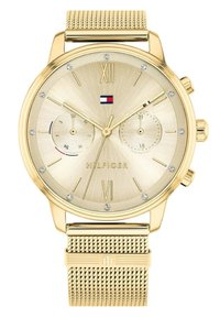 Montre dorée avec un cadran texturé, des chiffres romains, trois sous-cadrans et un bracelet en mailles. Présente un petit logo en rouge, blanc et bleu.