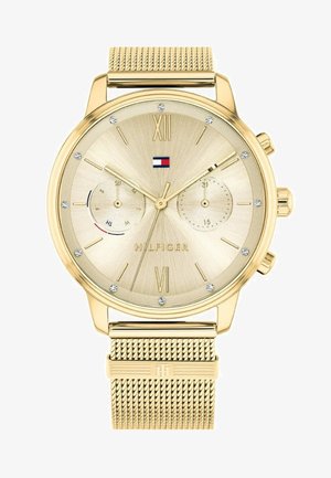 Montre dorée avec un cadran texturé, des chiffres romains, trois sous-cadrans et un bracelet en mailles. Présente un petit logo en rouge, blanc et bleu.