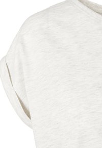T-shirt en coton beige clair à manches courtes, col rond et détails de manches retroussées.