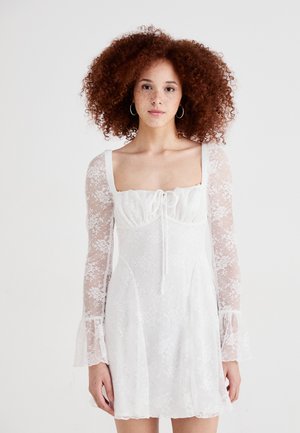 Rochie mini albă din dantelă florală transparentă, cu mâneci lungi evazate, decolteu pătrat și închidere cu legătură în față.