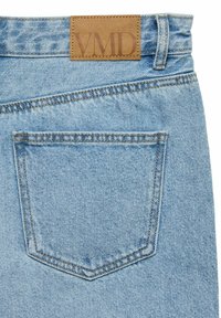 Lyseblå denimjeans har en brun lærlabel med prentet "VMD" i livet og en enkelt baklomme med en sydd kant.