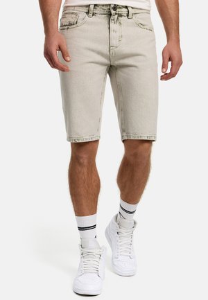 Lys grå denim shorts med lige skæring, fem lommer, frontknaplukning og synlige sømme. Bæres med hvide sneakers og stribede sokker.