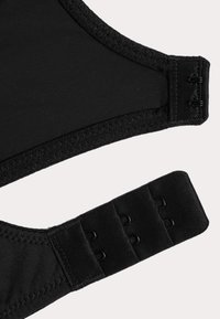 Section de soutien-gorge noir avec tissu lisse, fermeture réglable et détails de bande texturée. Comprend des crochets et une sangle réglable à trois niveaux.