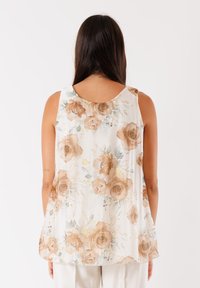 Tunic floreale senz maniche con una vestibilità ampia, caratterizzata da una base crema, grandi rose beige, foglie verdi e una texture morbida e leggera.