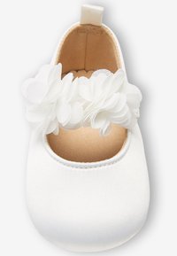 Zapato de bebé de satén blanco con tira de flor de tela y interior acolchado beige, diseñado para infantes.