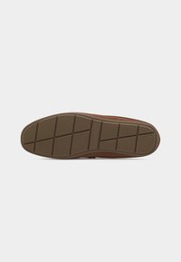 Semelle d'une chaussure marron avec un profil en caoutchouc à motifs comportant des rainures diagonales et horizontales sur un fond clair uni.