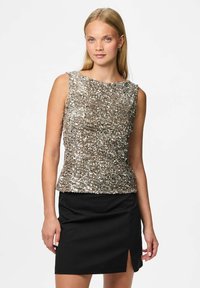 Top bez rękawów w metalicznym złocie z odblaskowymi cekinami, zestawiony z czarną mini spódnicą z bocznym rozcięciem. Gładka tekstura, dopasowany krój.